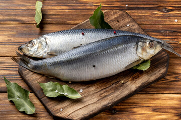 two salted herring on a wooden table with spices