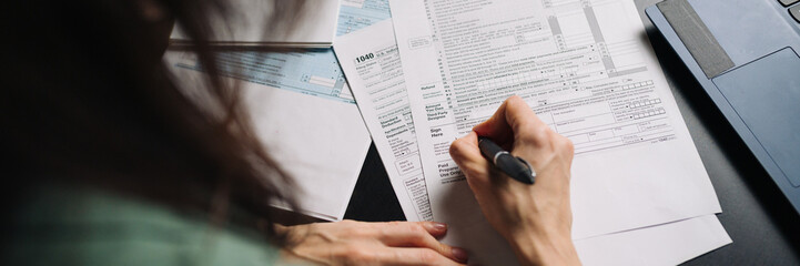 Woman filling US tax form 1040. tax form us business income office hand fill concept. Wide banner