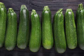 Raw ripe zucchinis on black wooden table, flat lay