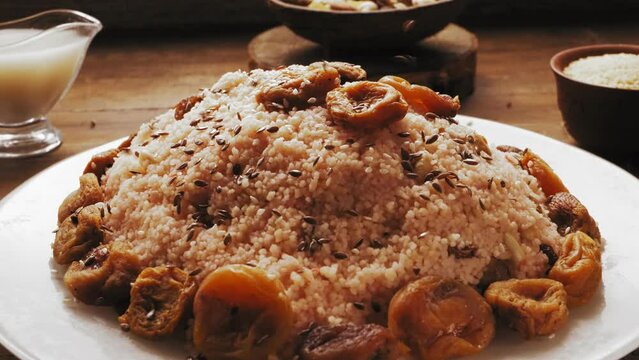 flax seed is poured into a plate with couscous with dried fruits and nuts