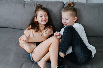 Two kids having a good time, trying to tickle each other's feet. - obrazy, fototapety, plakaty