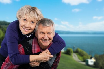 Senior man carrying his wife on his shoulders laughing. Attractive crazy old senior couple