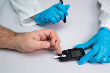 Doctor piercing patients finger with lancet in clinic closeup. Blood glucose control concept