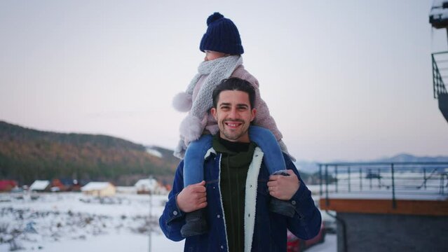 Happy young father on winter holiday with small child outdoors in snowy nature.