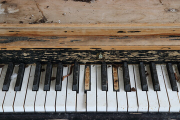 Close-up shot of an old piano with damaged keys covered in dust