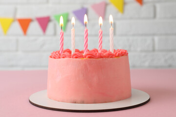 Cute bento cake with tasty cream and burning candles on pink table