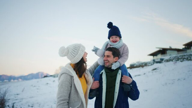 Happy young family on winter holiday with small child outdoors in snowy nature.