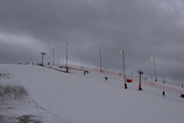 Distance view at a ski slope. Looking up angle or view. Gray clouds in the sky. Swedish resort...