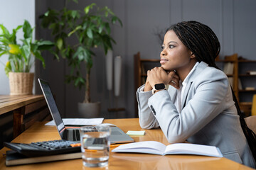 Distracted from work young african american businesswoman sitting at office desk with laptop look...