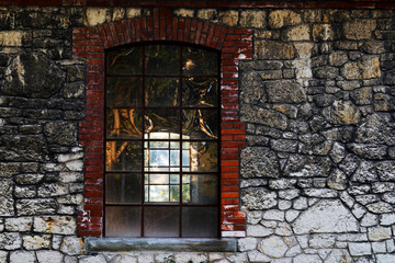 Ein altes durchscheinendes Fenster in einem leerstehenden Gebäude mit Steinmauer