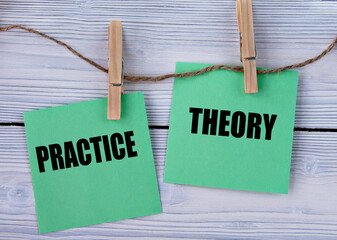 PRACTICE and THEORY - words on green pieces of paper with clothespins on a light wooden background