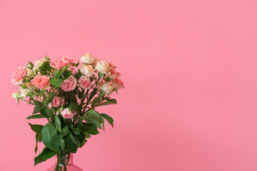 Vase with beautiful roses near pink wall, closeup