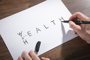 Man writes Wealth to Health text with a marker.