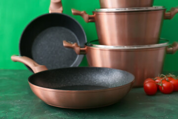 Copper frying pan on green background, closeup