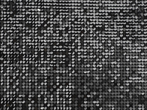 Abstract background with flickering and glittering silver metallic particles or sequins on the wall.