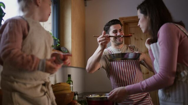 Happy young family with small child cooking together in cabin on holiday.