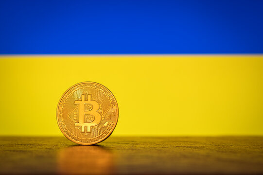 Bitcoin physical golden coin with Ukraine flag in the background - Powered by Adobe