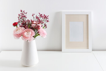Bouquet of red and pink Persian buttercups on a white table. Scandinavian style. Place for text....