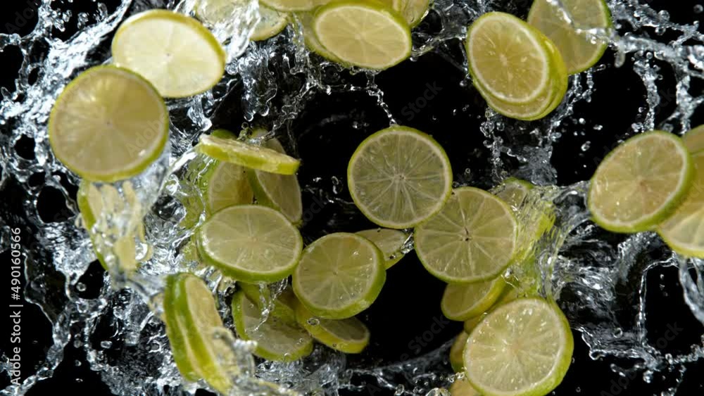 Poster super slow motion of rotating lime slices with splashing water, black background. filmed on high spe