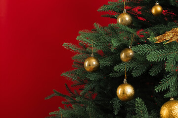 Naklejka na ściany i meble Beautifully decorated Christmas tree on red background, closeup. Space for text