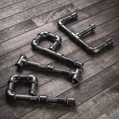 Cast iron pipes and fittings in a shape of word pipe on a rustic wooden table