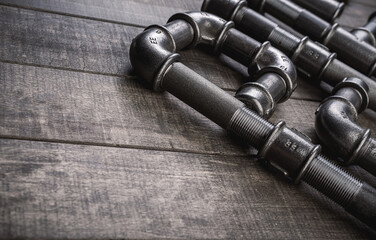 Cast iron pipes and fittings of different shape and forms, laying on a rustic wooden table