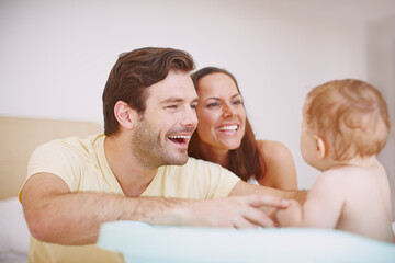 Bathtime- a joyful experience for all of them. Two joyful parents bonding with their baby daughter at bathtime.