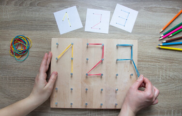 a children's educational game - hands add up numbers . a board with carnations. early development . study of numbers. nearby are cards with numbers, pencils, multi-colored rubber bands