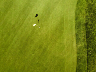 Aerial top view of a yellow flag with a shadow on the grass in a golf course