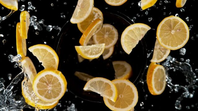 Super slow motion of rotating lemon slices with water, black background. Filmed on high speed cinema camera, 1000 fps. Speed ramp effect.