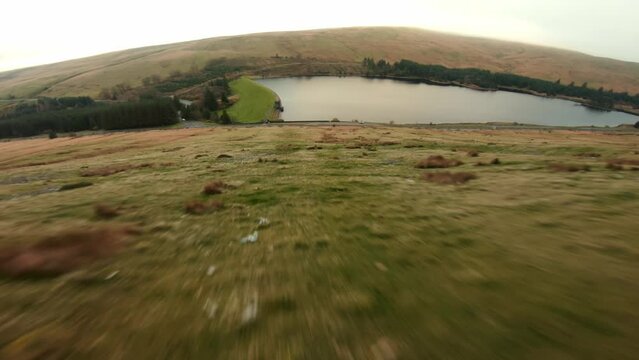 Aerial drone shot of Brecon Beacons with reservoir at the botom next to pen y fan peak. Drone video of fast flowing fpv view wales uk