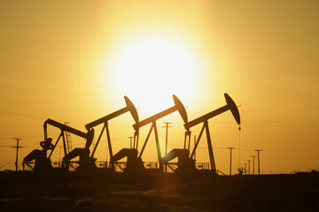 Four oil well pump jacks at sunset
