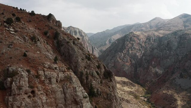 Drone movement over Armenian giant, tall brick red cliffs and rocks near Noravank monastery