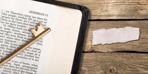 God Bible with an old, vintage key on a wooden table. Christian biblical concept of Jesus Christ's grace and love.