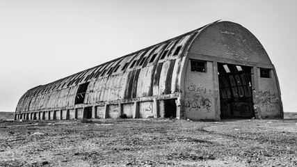Grayscale of a hangar in the field - obrazy, fototapety, plakaty