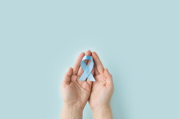 World diabetes day. Blue ribbon in woman hands on a blue background. 14 november. November Men health awareness, November Blue.