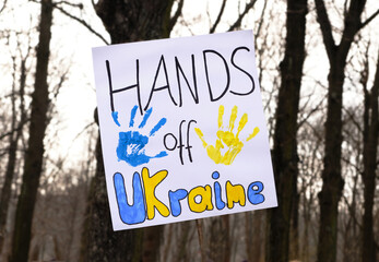 Text Hands off Ukraine on white packard. Closeup on packard with with text and hand prints. Protest against war in Ukraine. WInter forest as background.