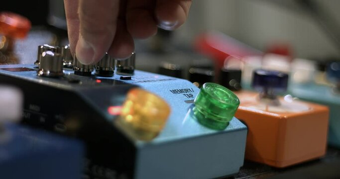 Musician Pressing Effect Pedal Then Adjusting Control Knobs. Close Up Effects Pedalboard.
