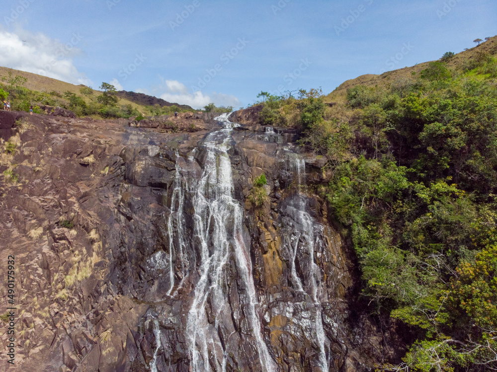 Sticker Beautiful photo of a waterfall, rocks and trees in nature on a sunny day