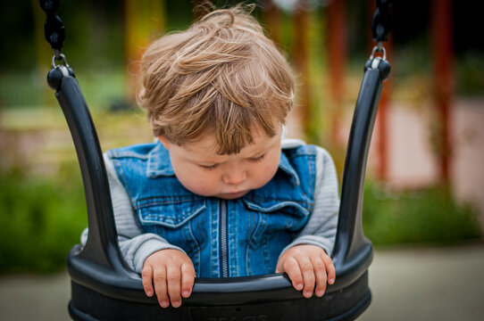 Boy in jeans jacket sittning in Swing