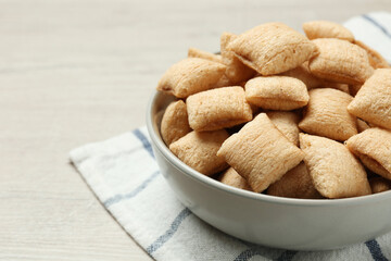 Bowl of sweet crispy corn pads on white wooden table, closeup view with space for text. Breakfast cereal
