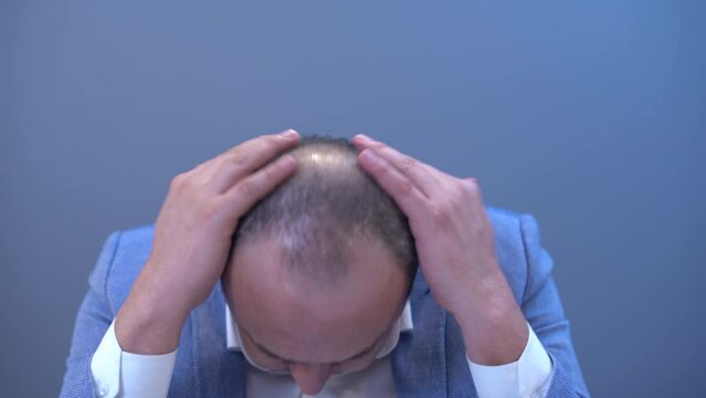 Bald man playing with his scalp. 
The bald man plays with his scalp and then puts on a wig. She is happy with the wig and laughing.
