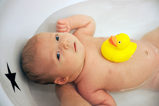 Baby boy in bath with duck on stomac