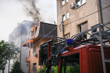 Close-up picture of blue lights and sirens on a fire truck, with burning building in background.