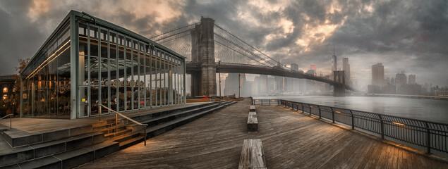 Panoramic view from pier of Manhattan and Brooklyn bridge under the cloudy sky, New York City
