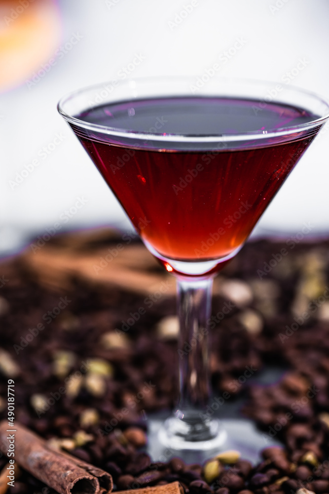 Wall mural Vertical shot of a red cocktail in a martini glass on a bar with coffee beans