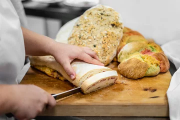 Printed kitchen splashbacks Bread Young baker cutting the freshly baked bread on a wooden board