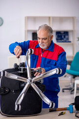 Old male repairman repairing office chair