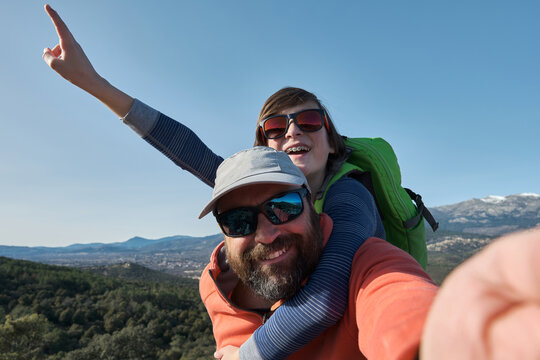 A Teenage boy with braces and father taking selfie during hiking in nature