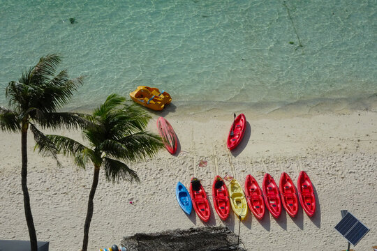 Aerial view of coconut trees and colorful aligned Kayak Sailing boats on the Tumon Beach, Guam